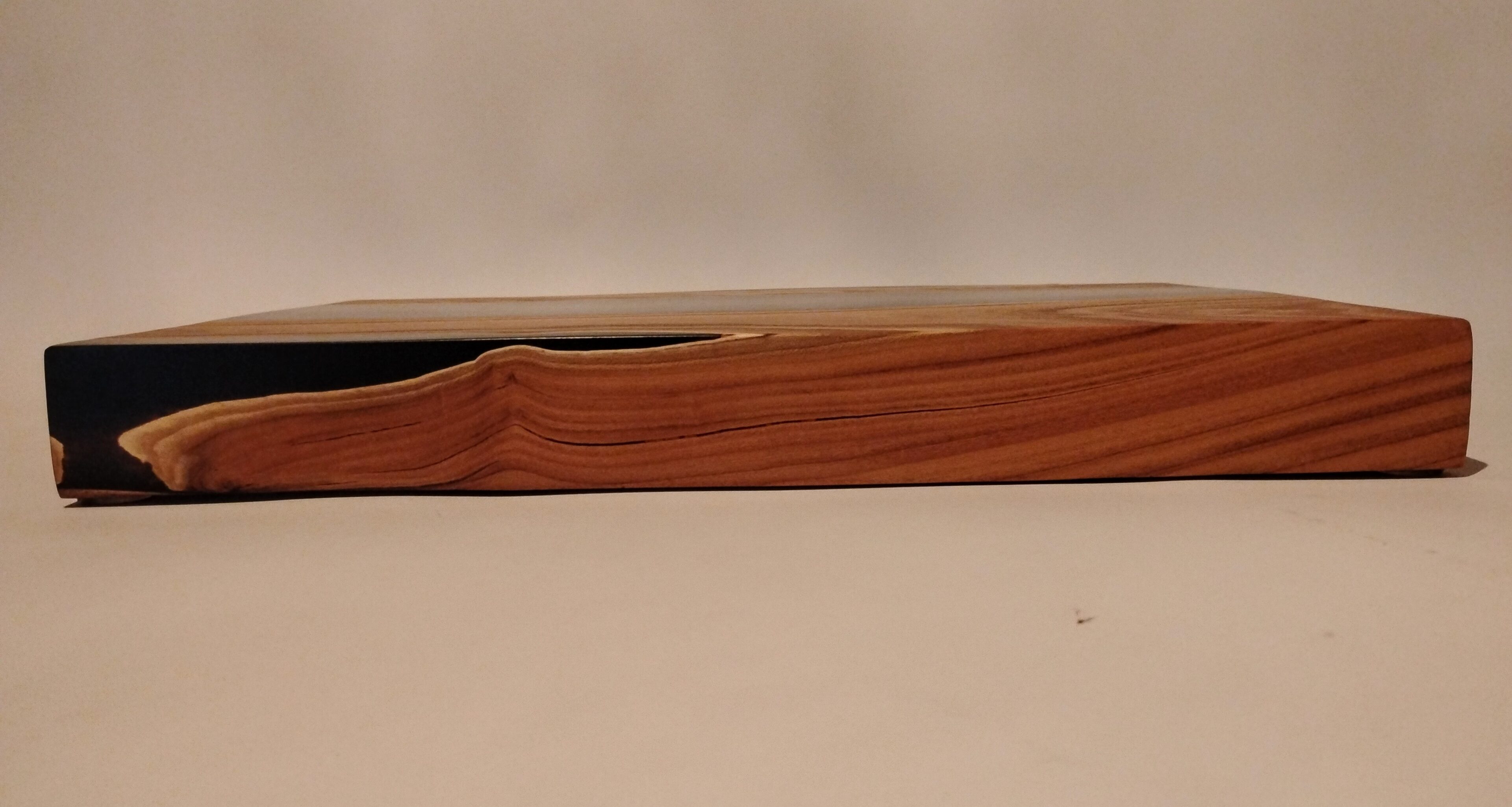 A close-up of a wooden object with a curved groove on a beige surface.