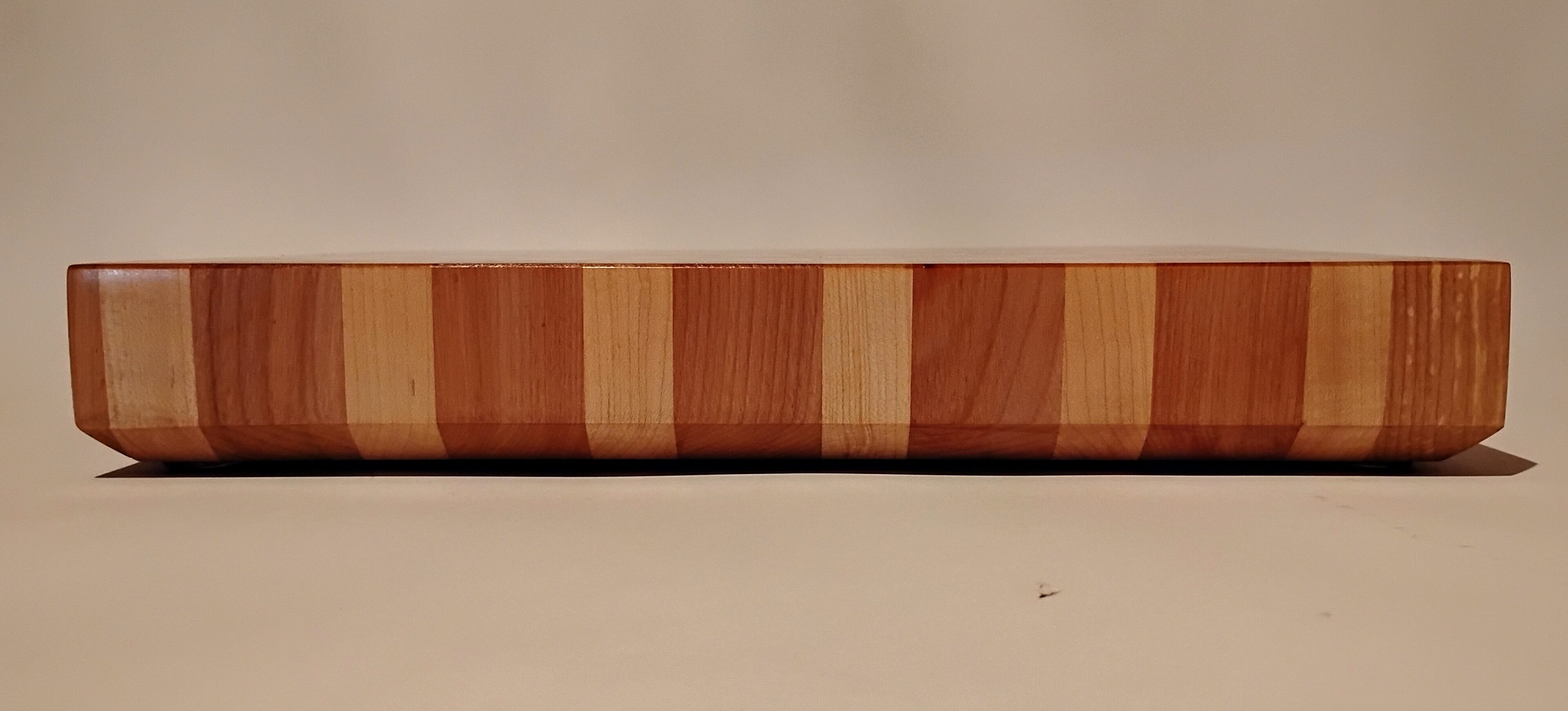 A wooden cutting board with distinct wood grain patterns on a beige surface.