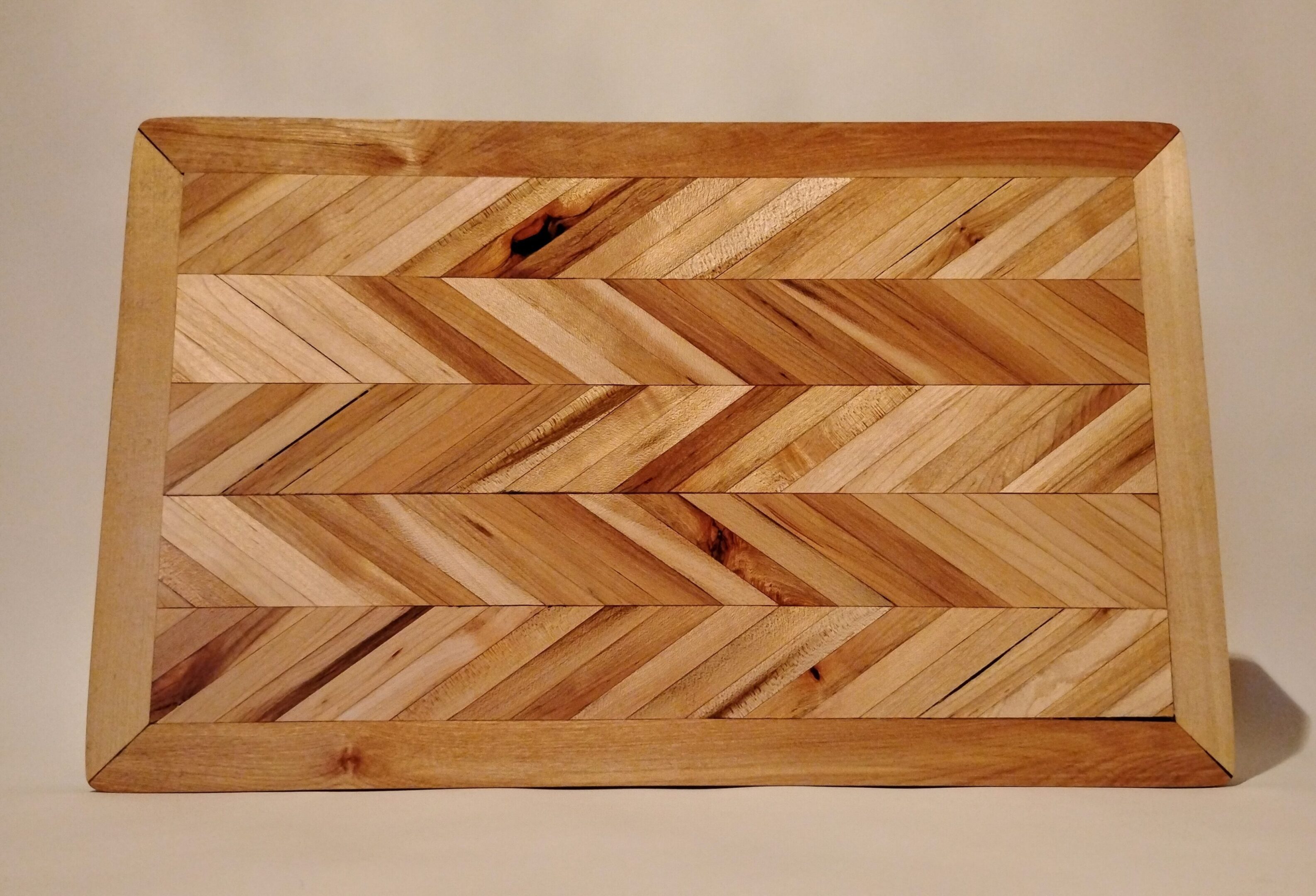 Wooden surface with a herringbone pattern and a small defect.