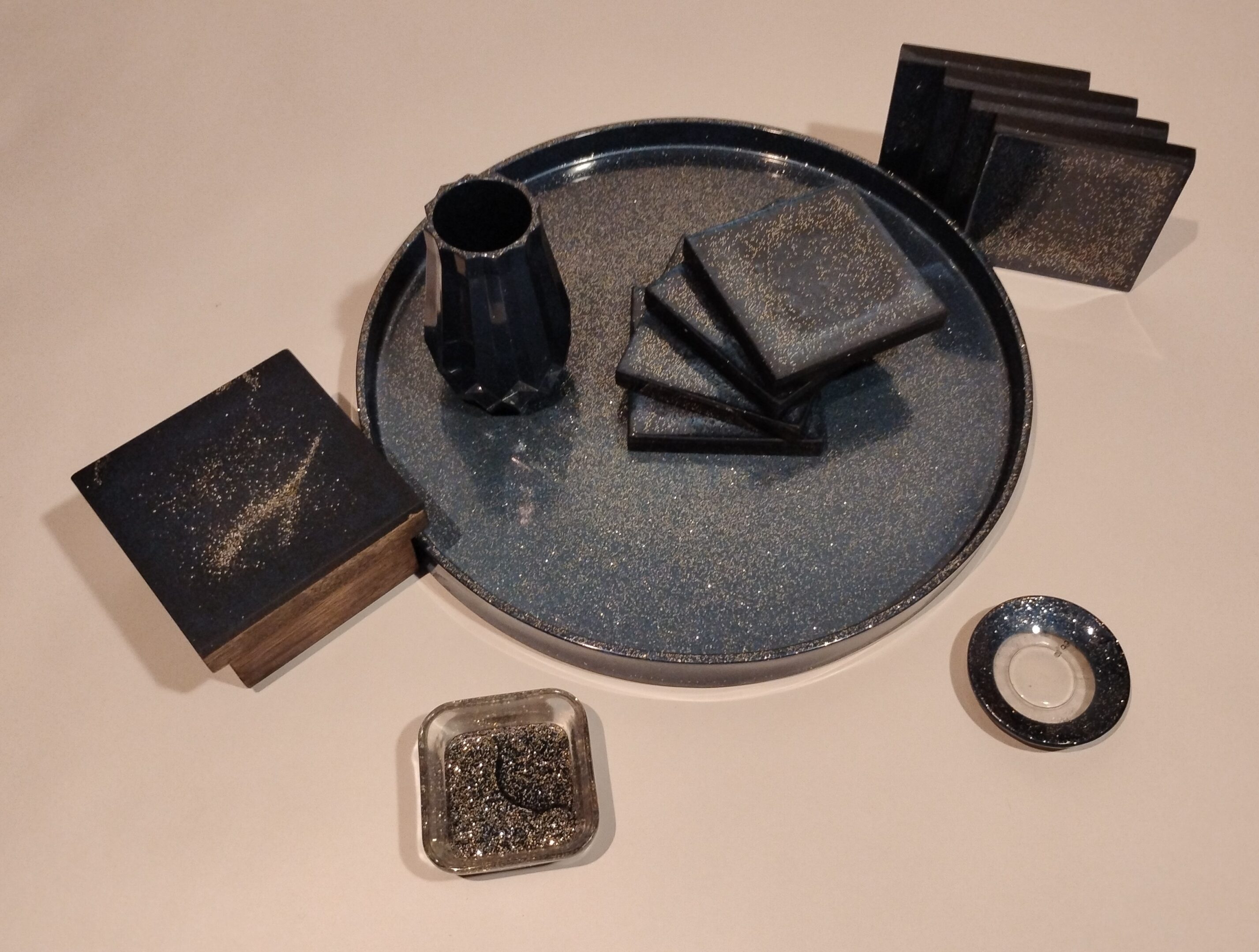 A ceramic tray with coasters, a vase, and decorative boxes on a wooden surface.