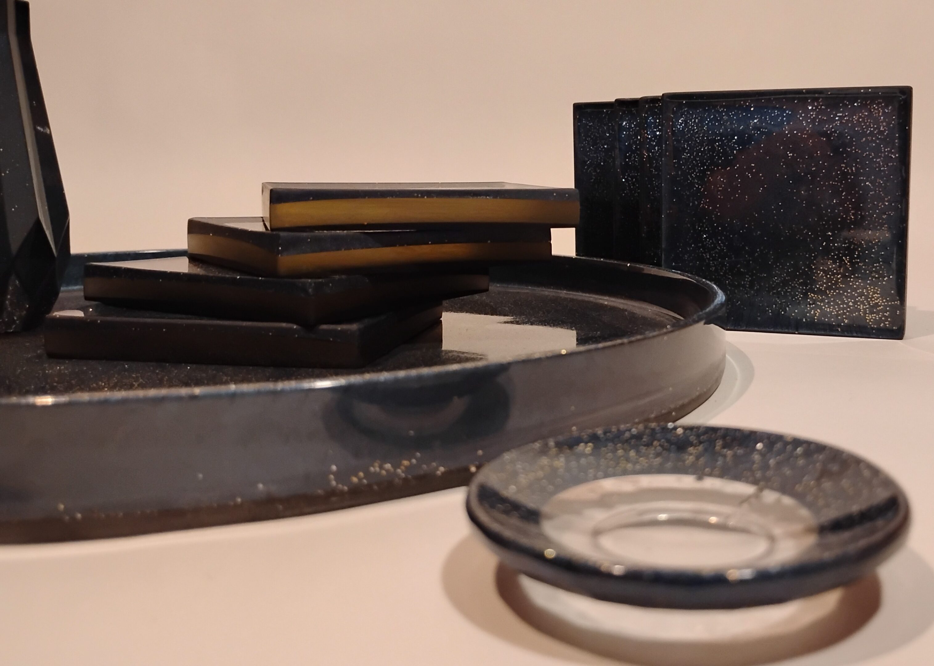 Close-up of black jewelry boxes and velvet trays on a beige surface.