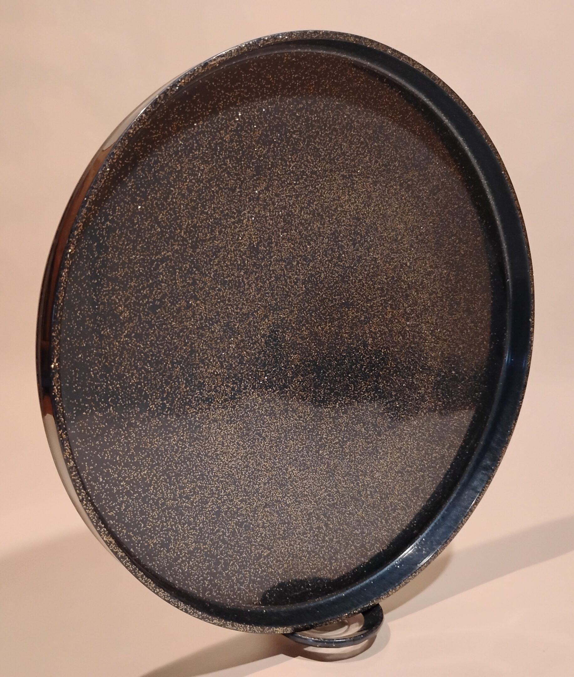 Round black tray with a textured surface and a raised edge.