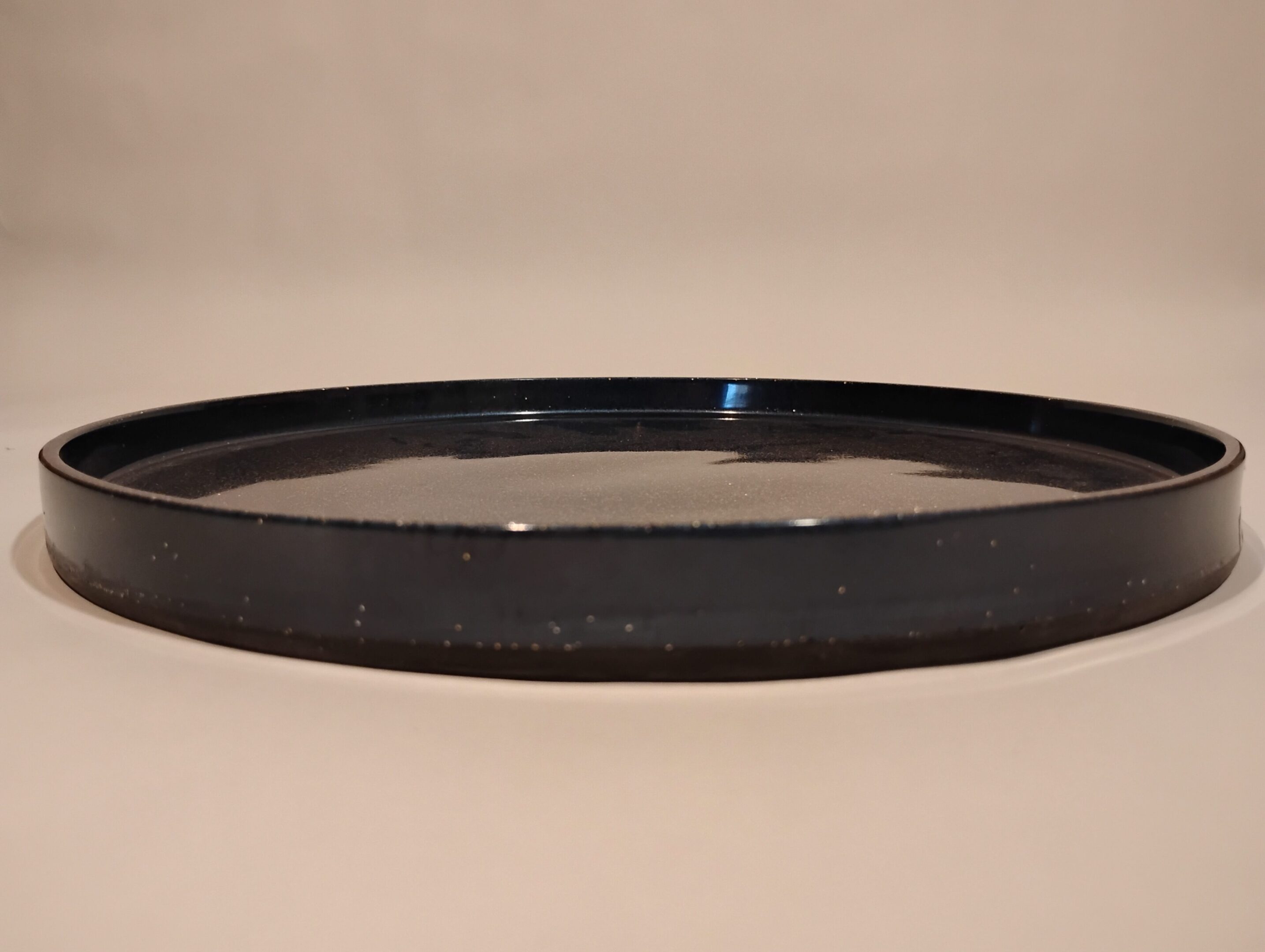 A close-up of a black circular filter on a beige surface.