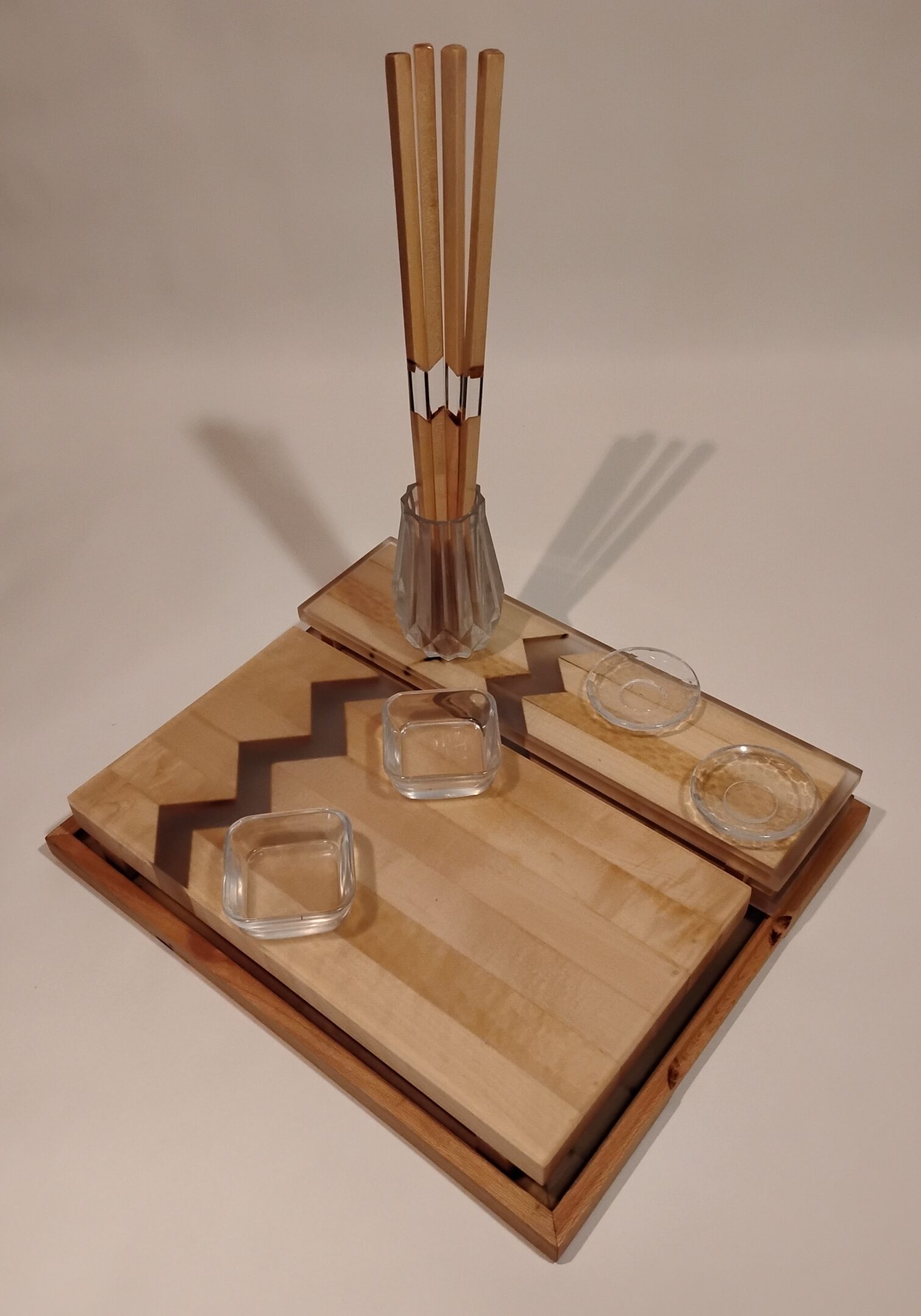 A wooden board game with glass pieces and a stick for playing.