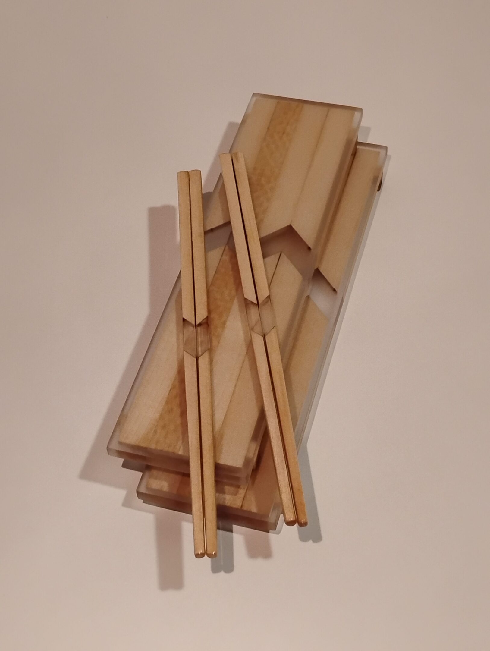 Wooden chopsticks resting on a wooden holder against a plain background.