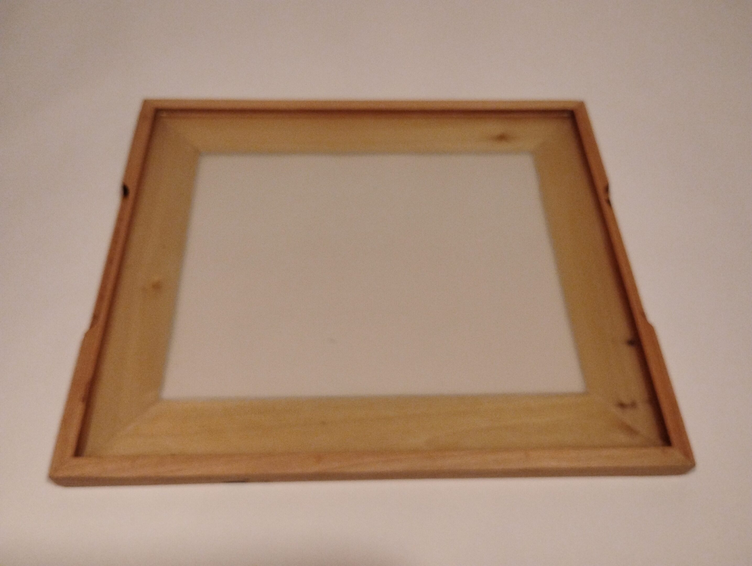 Empty wooden picture frame with canvas backing.