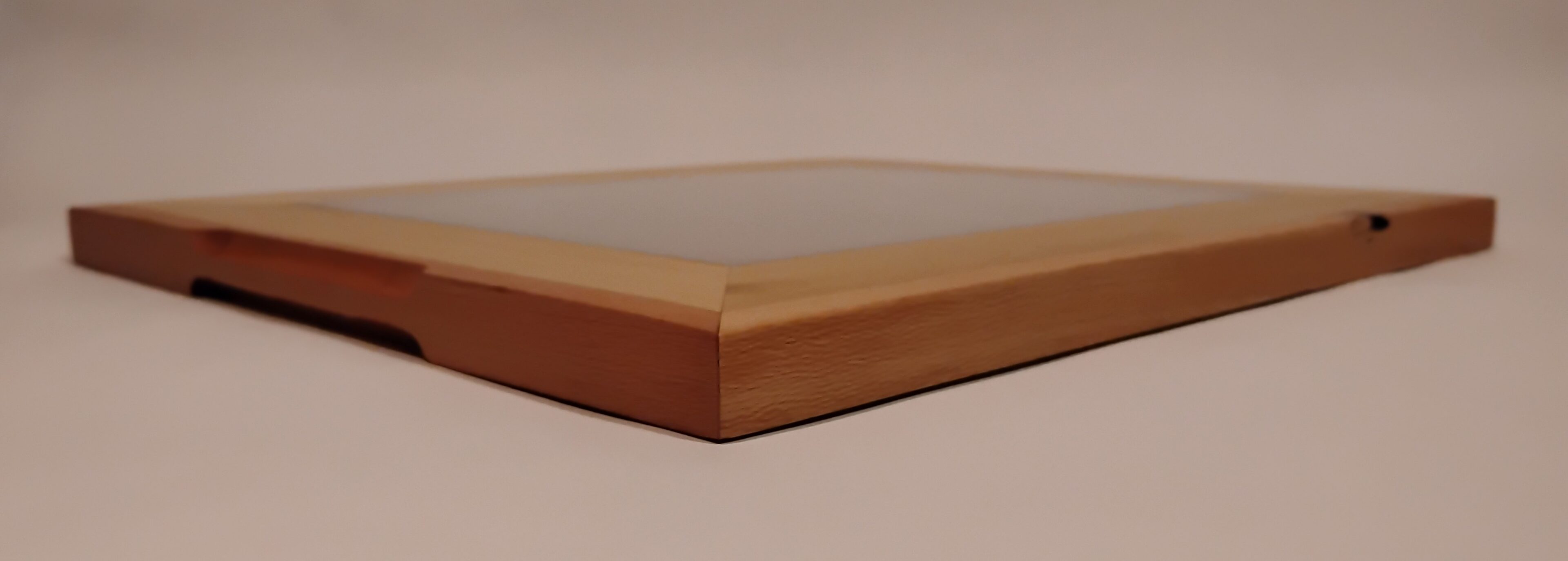 Close-up of a wooden cutting board with smooth edges on a light surface.
