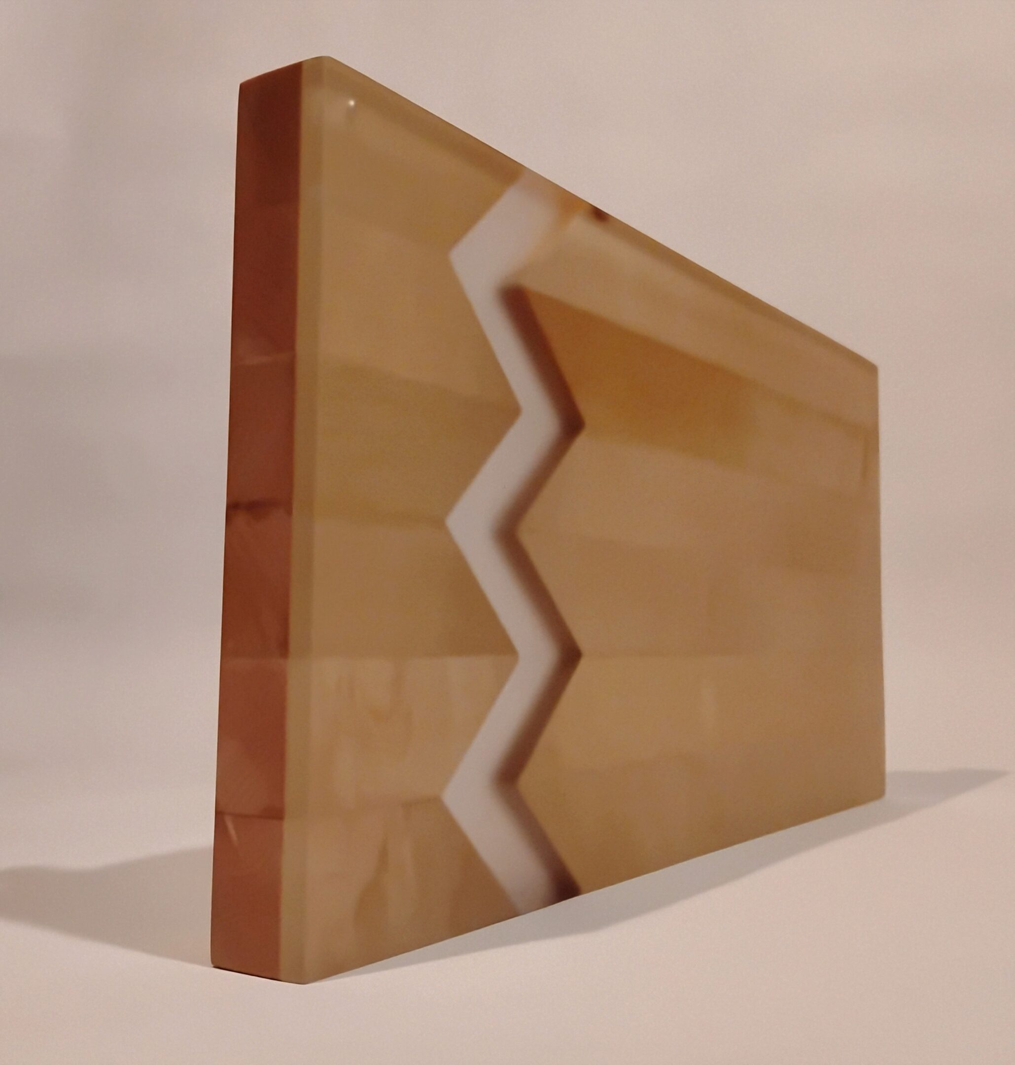 A zigzag-patterned wooden artwork with layered colors.