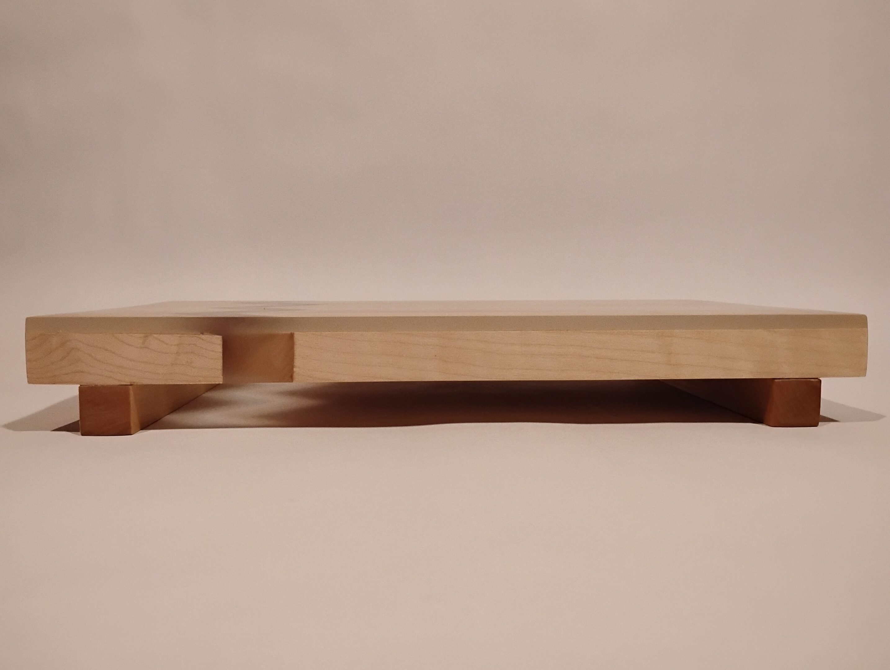 Minimalist wooden bed frame with built-in side tables in a neutral bedroom.