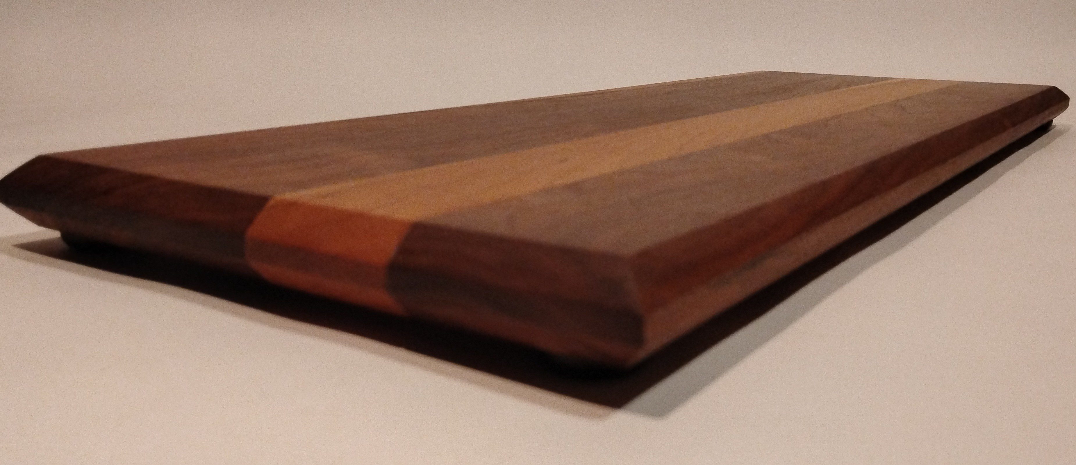 Close-up of a wooden cutting board with smooth edges and two-tone wood grain.