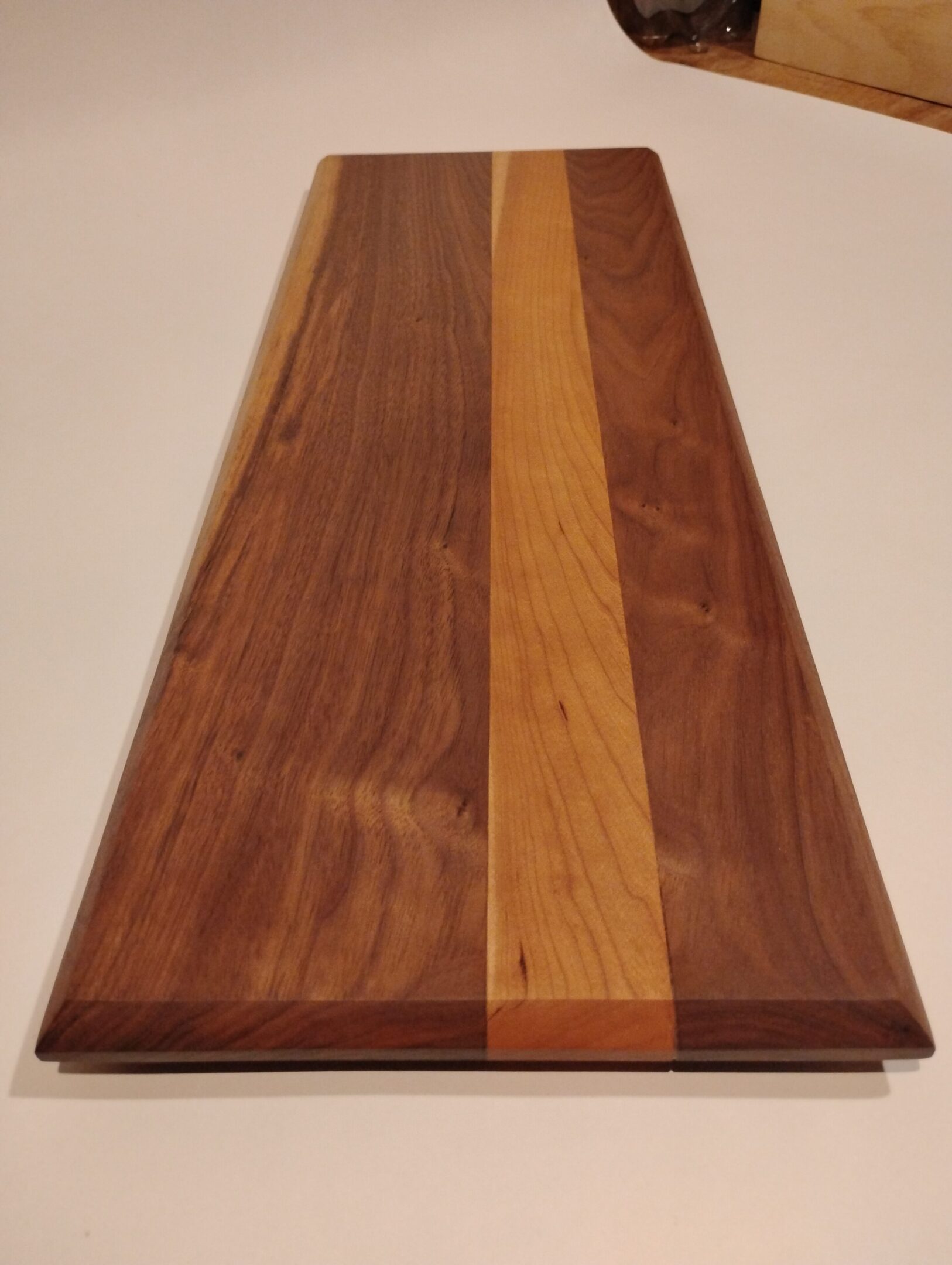 Close-up of a polished wooden board with two contrasting wood tones.