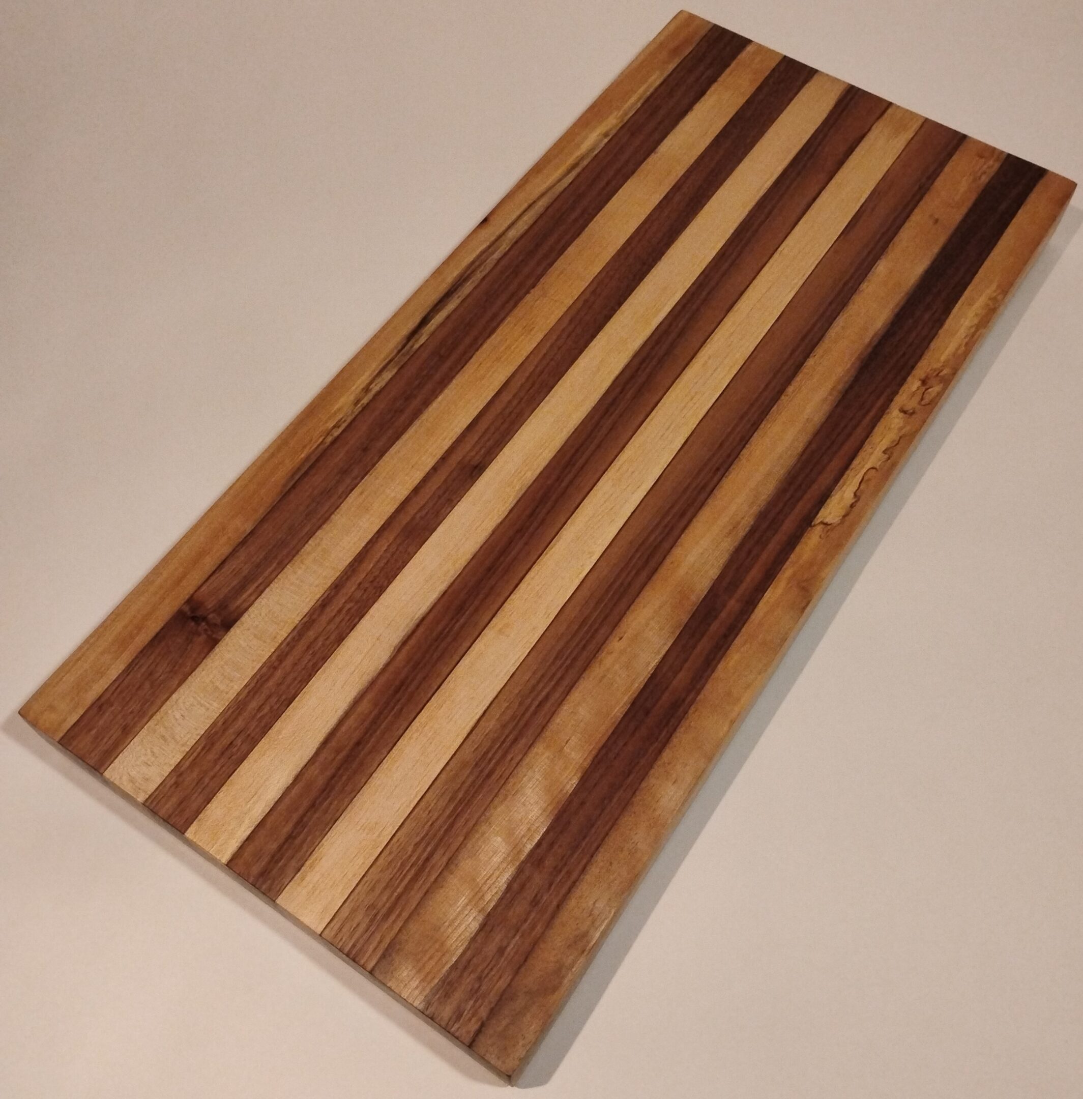 Striped wooden cutting board with alternating light and dark wood.