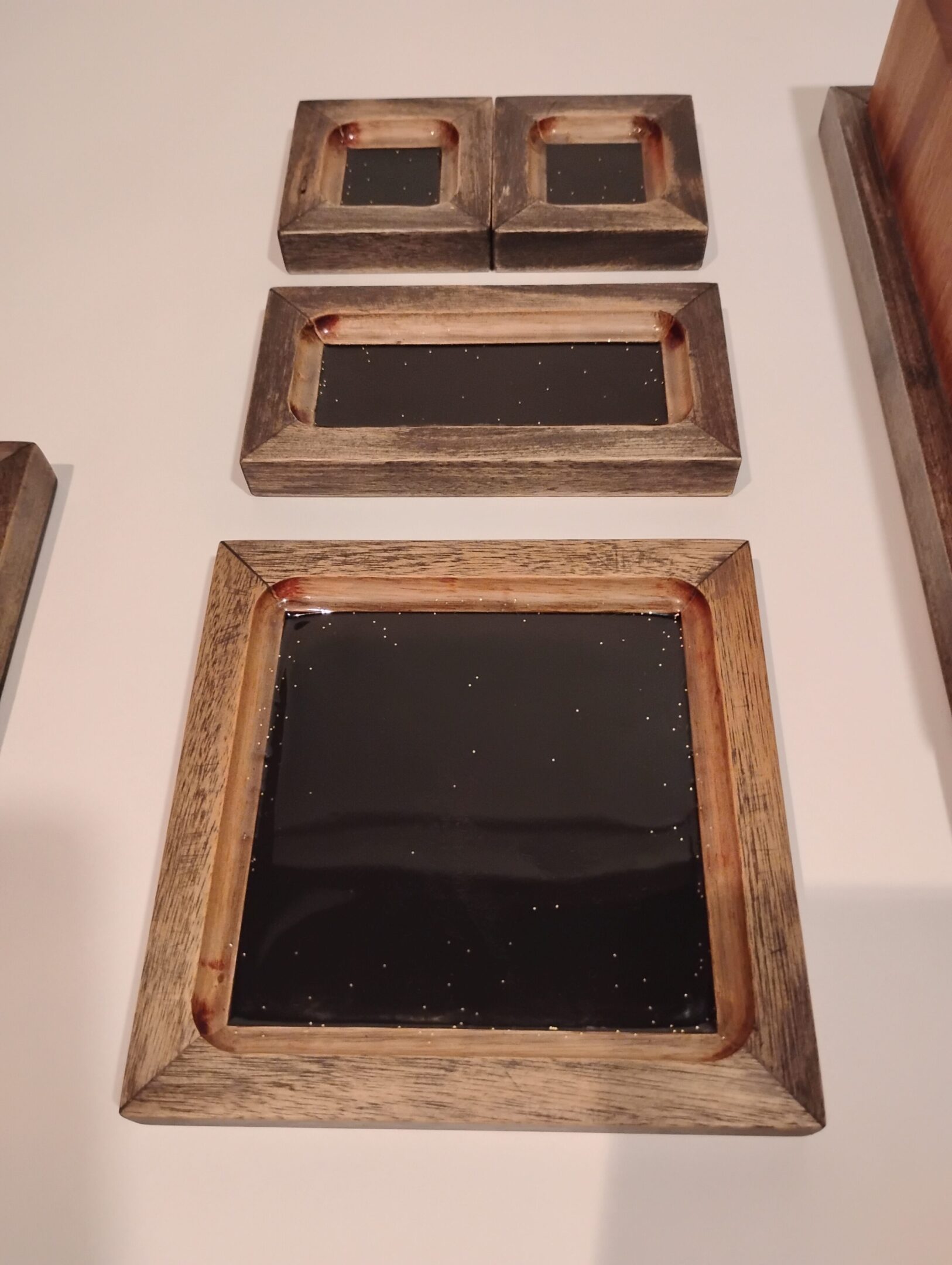 Three empty vintage wooden frames with black centers hung on a wall.