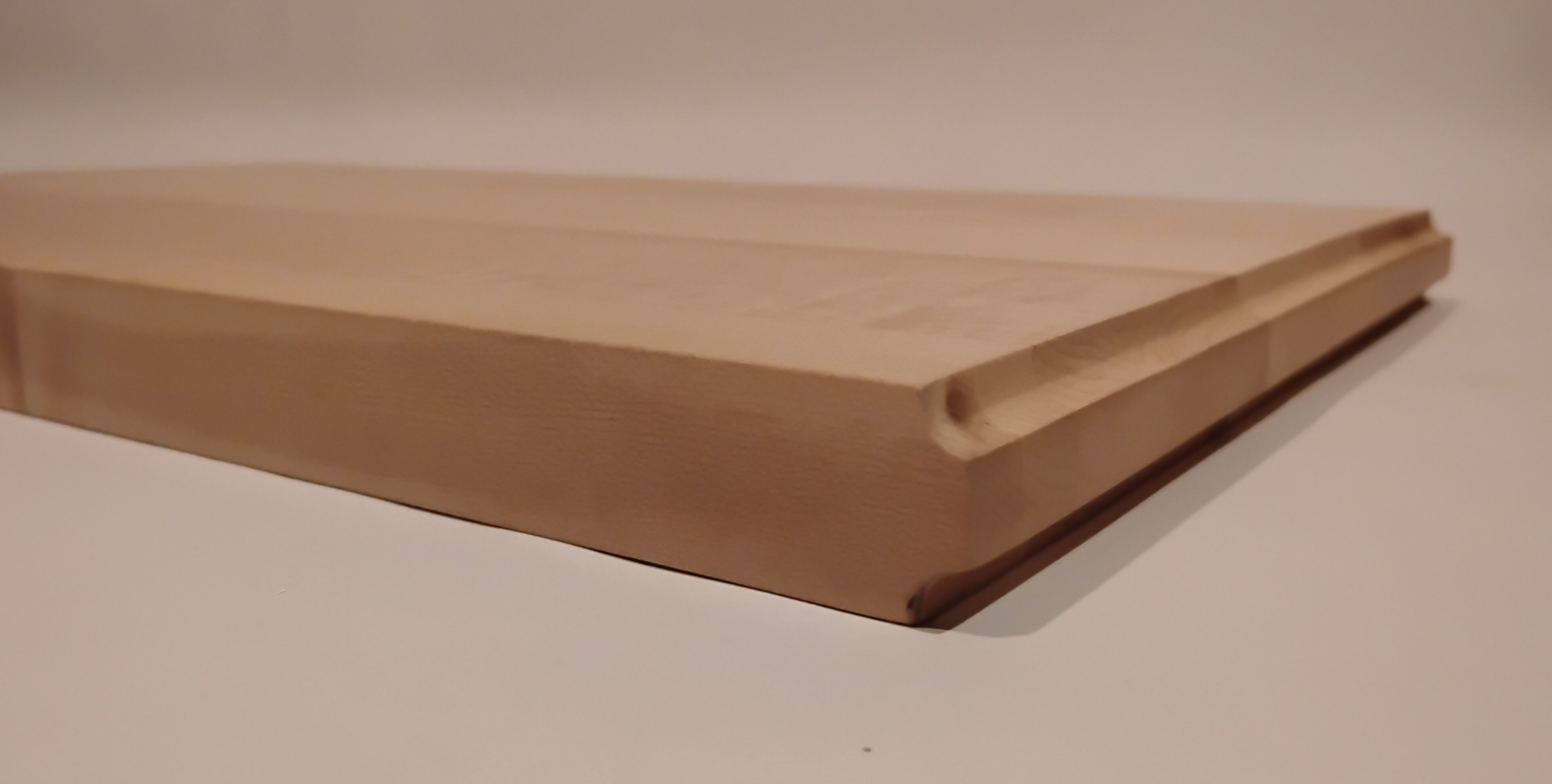 Close-up of a wooden cutting board edge with a groove for catching liquids.