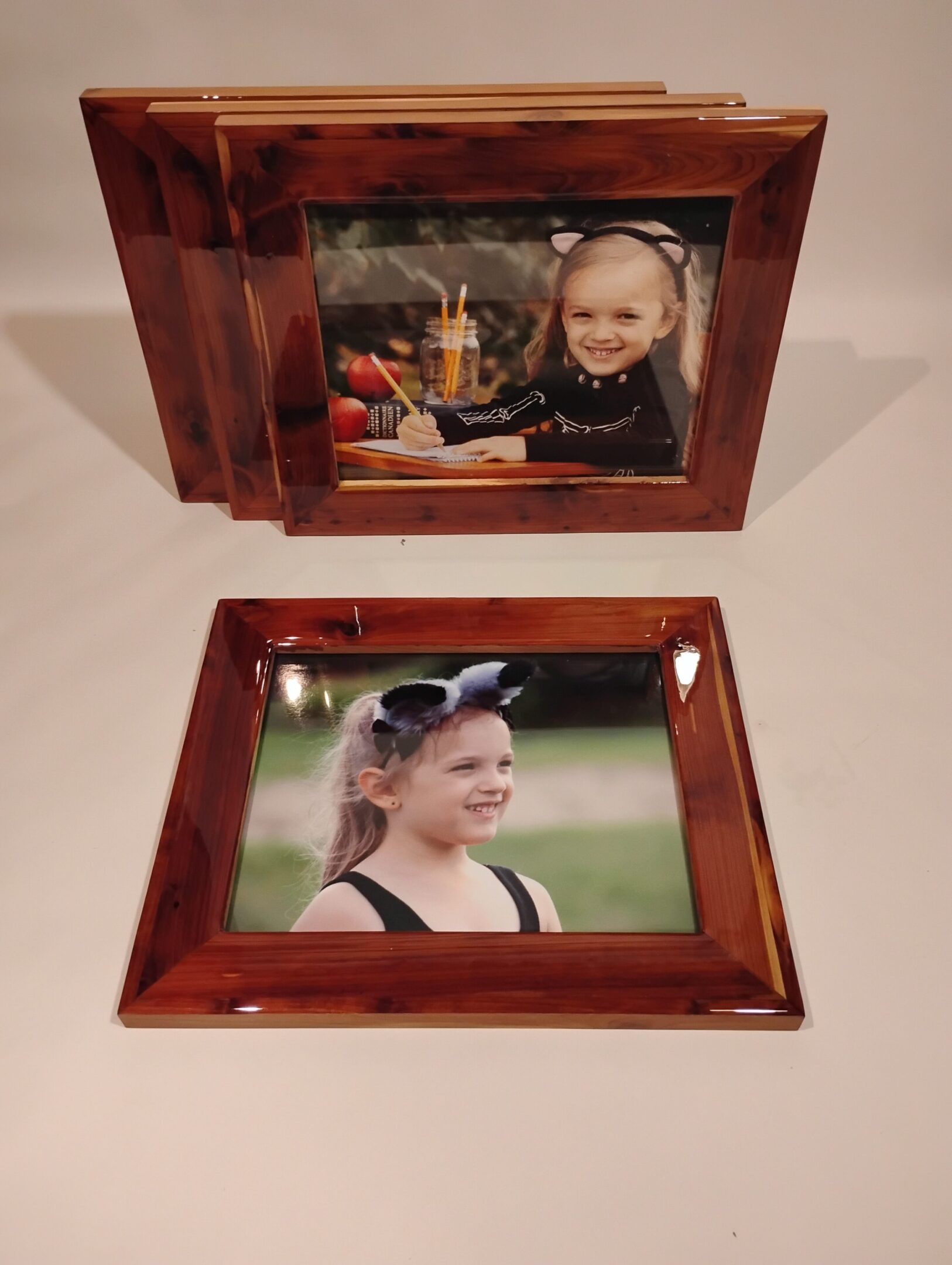 Two wooden photo frames holding portraits of children.