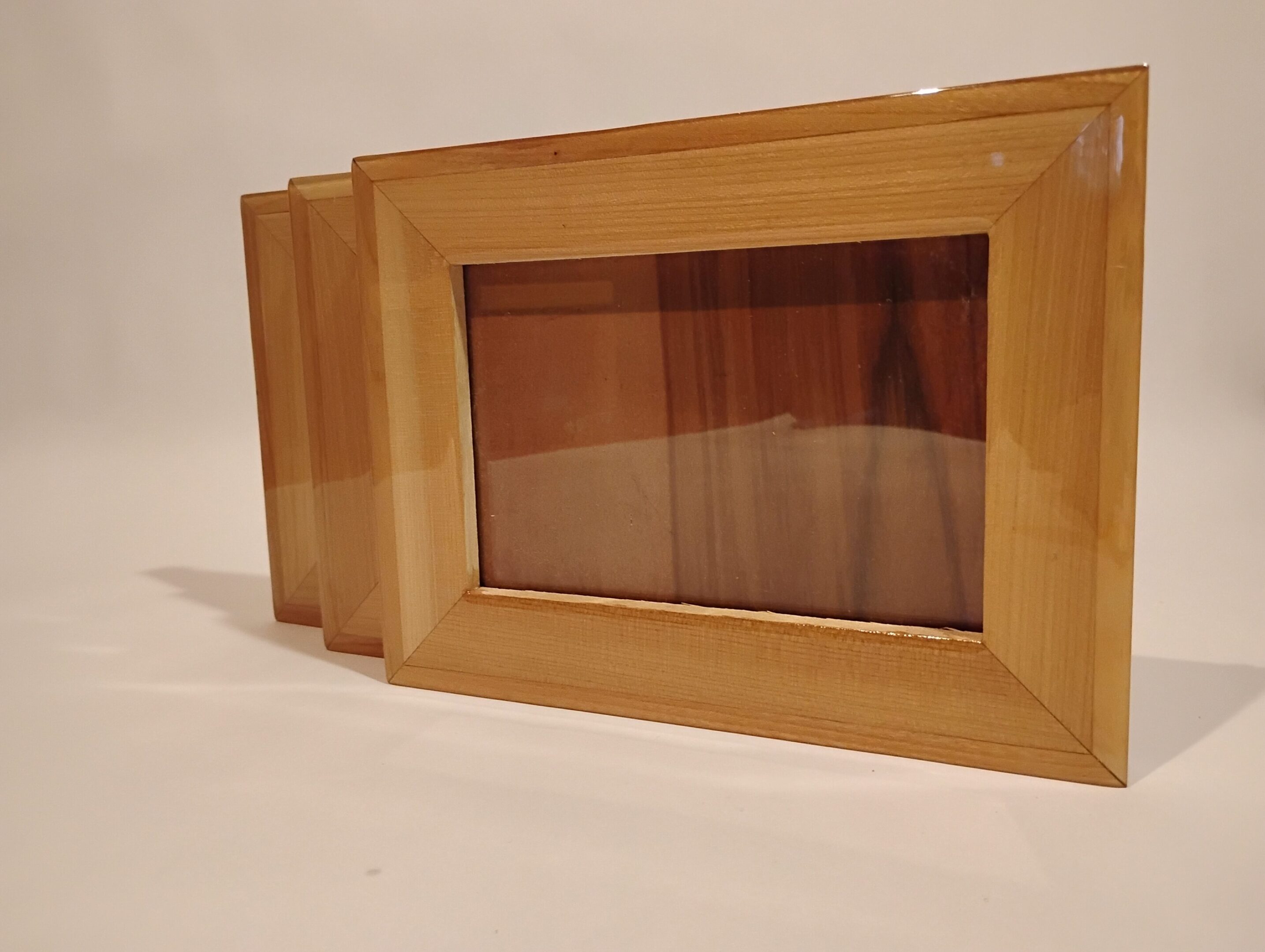 Wooden picture frames with glass fronts stacked together.