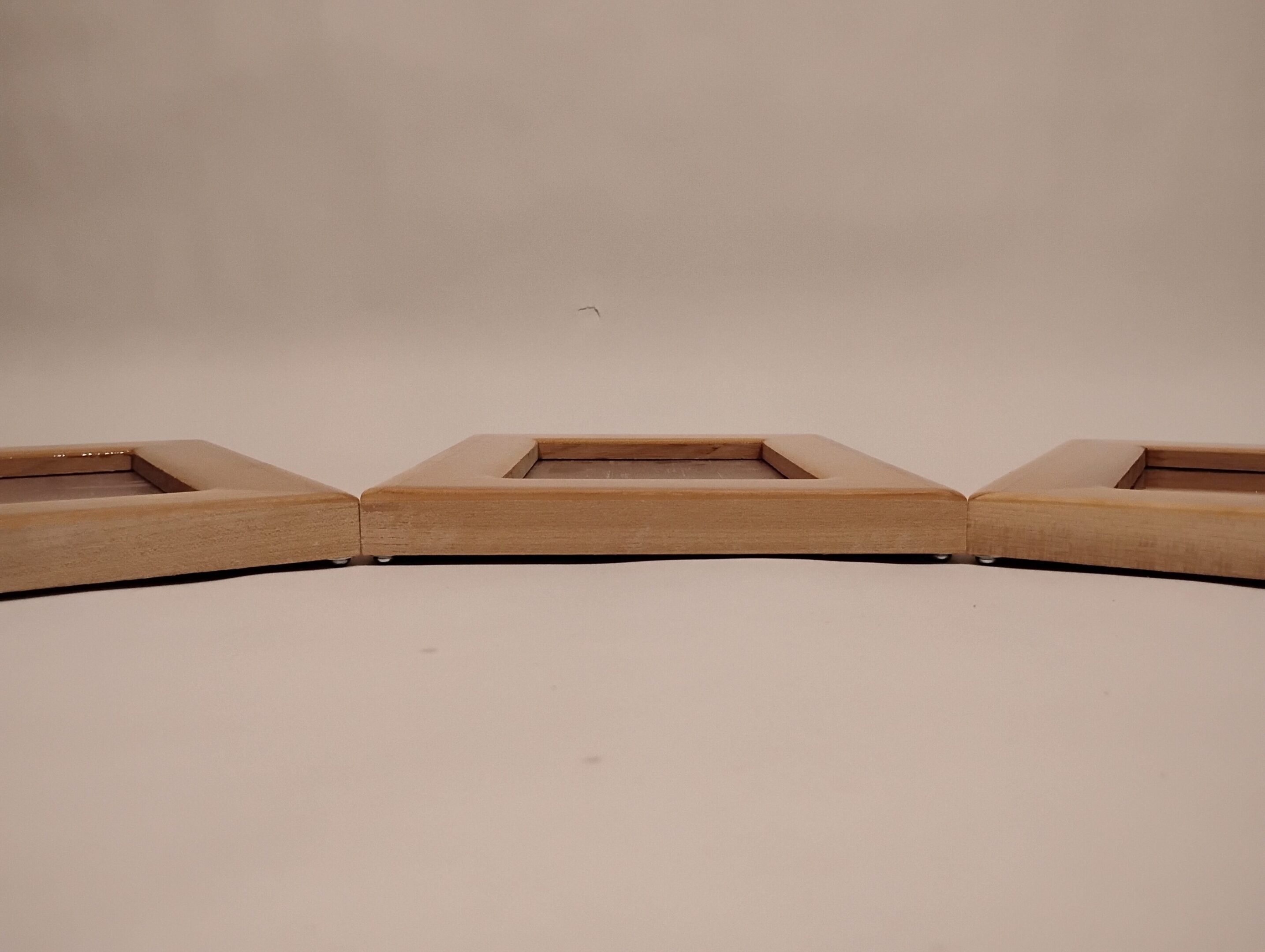Close-up of a wooden object with rectangular cutouts on a neutral background.