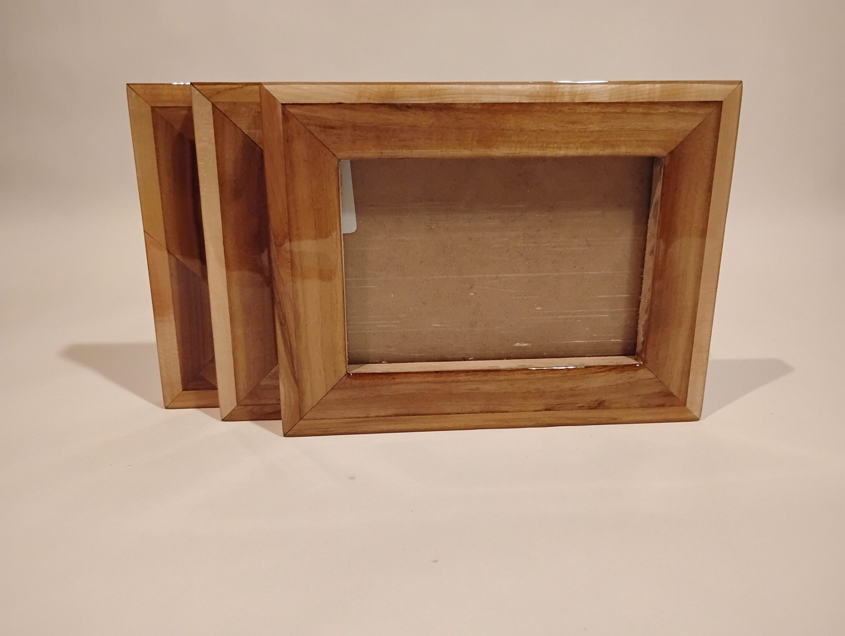 Three empty wooden photo frames stacked together on a white surface.
