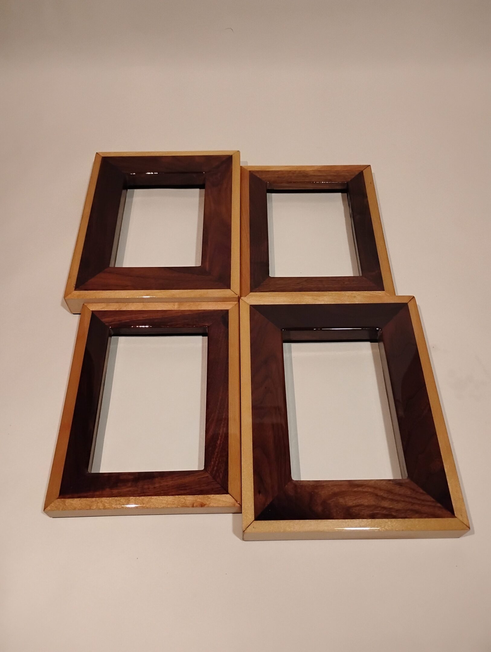 Four empty wooden picture frames arranged in a square on a surface.