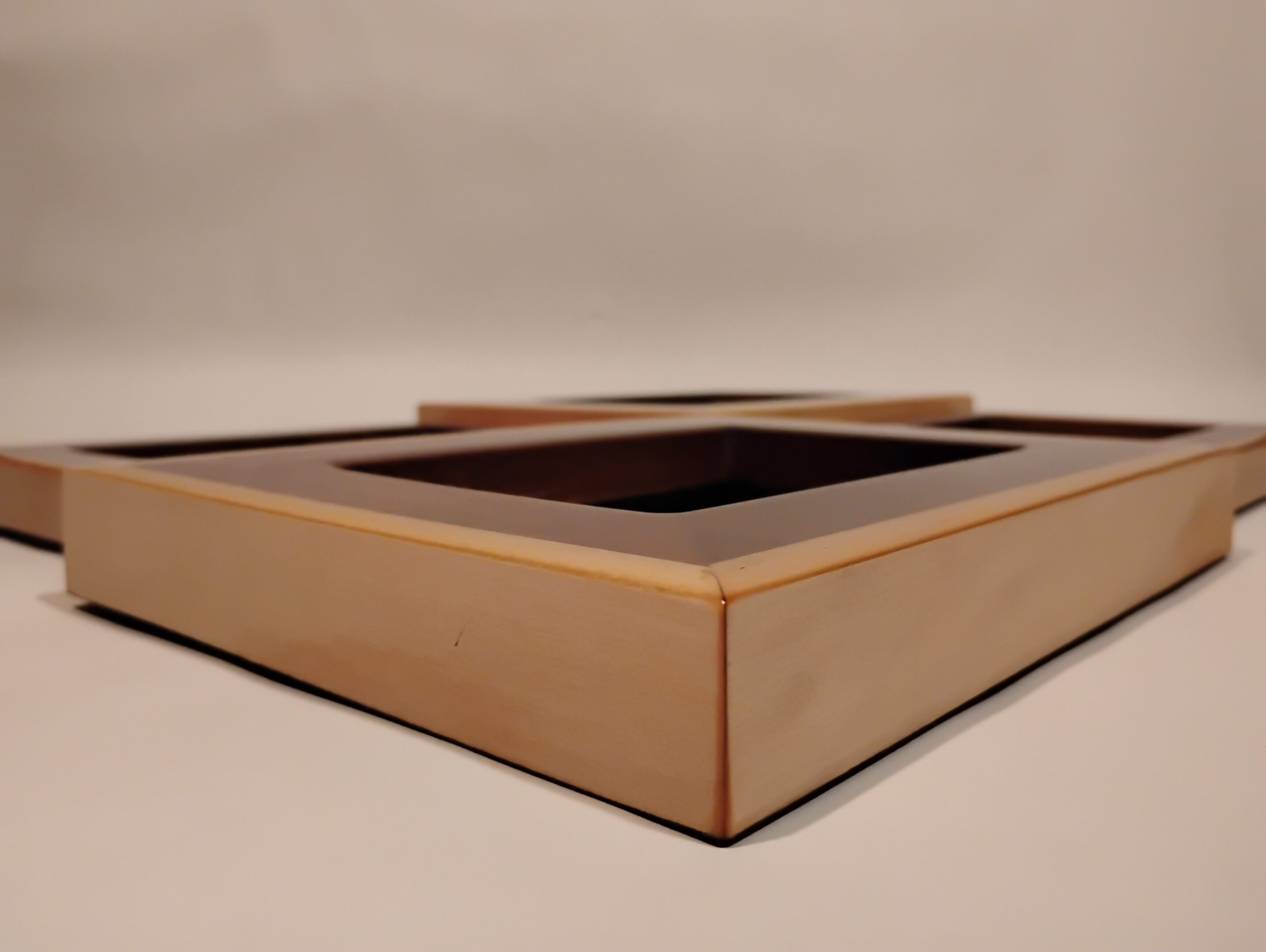 Close-up of a wooden picture frame corner on a neutral background.