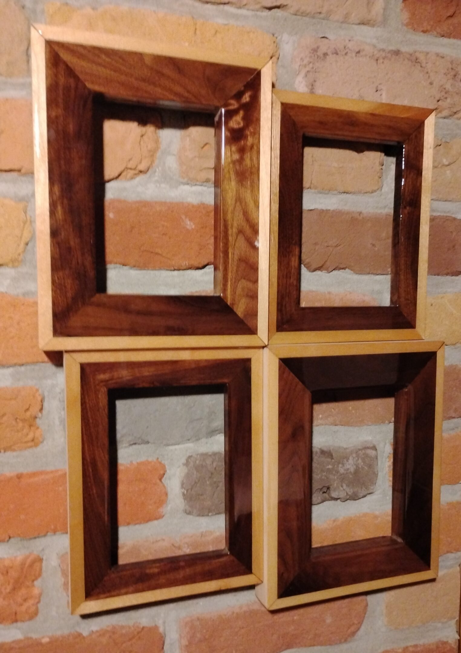 Four wooden picture frames arranged on a brick wall.