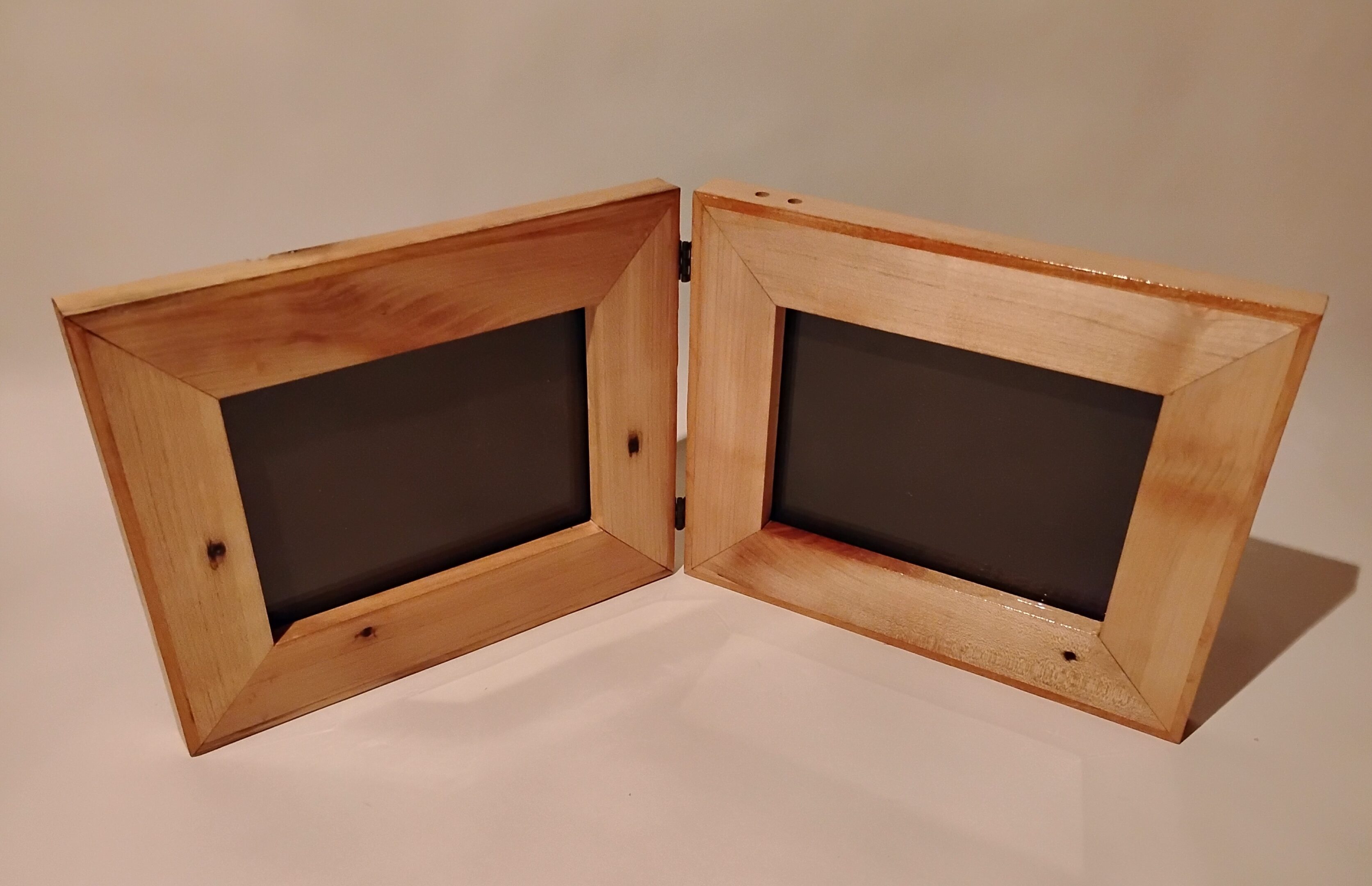 A wooden double photo frame with two empty black photo slots.