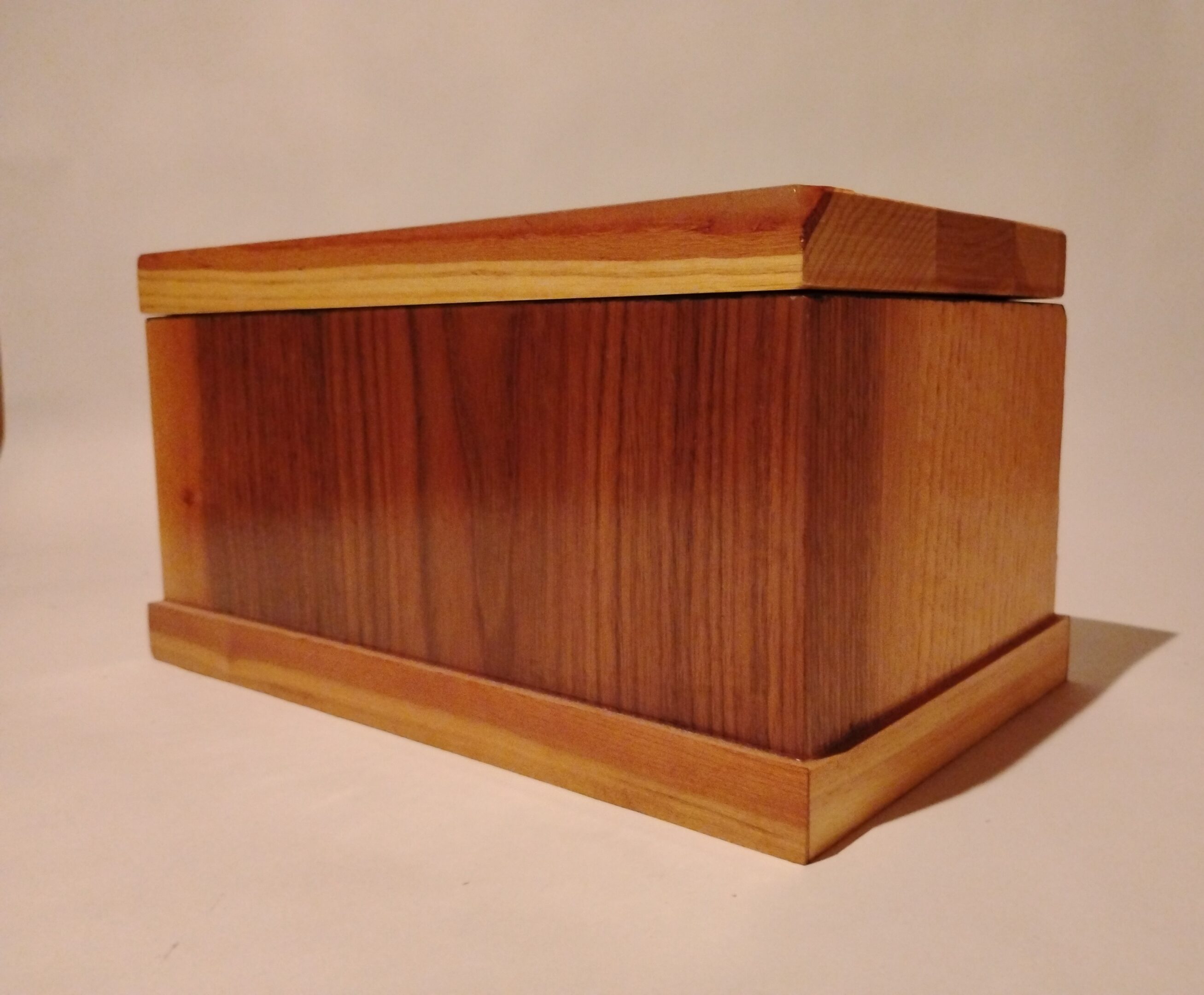 A polished wooden box with a smooth finish and lighter trim edges.