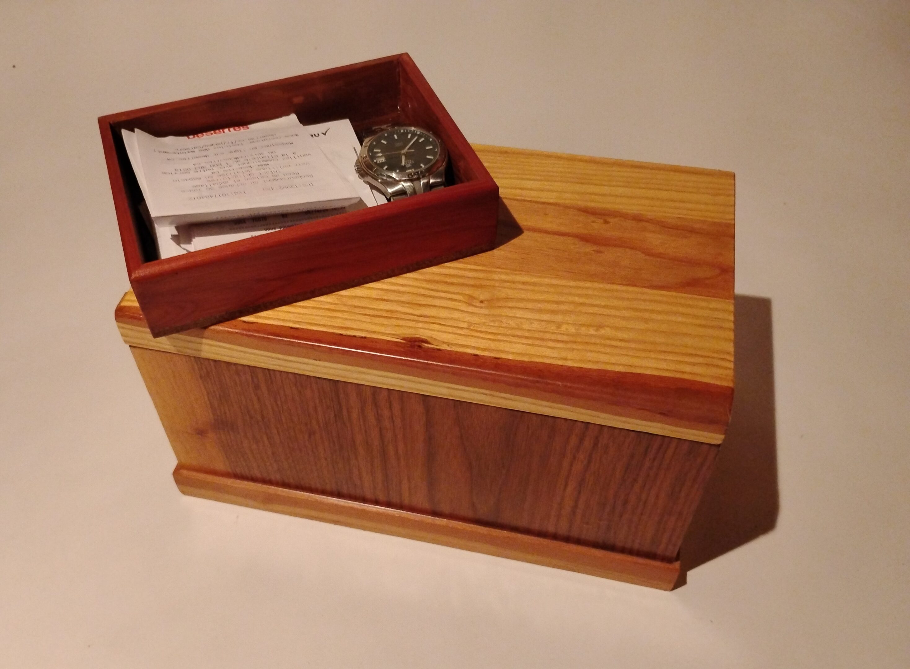 Wooden box with a small compartment holding a coin and papers.