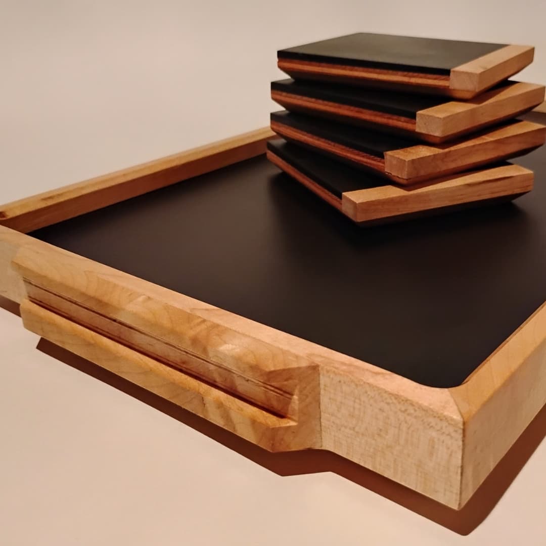 Stacked wooden trays with a black base on a light surface.
