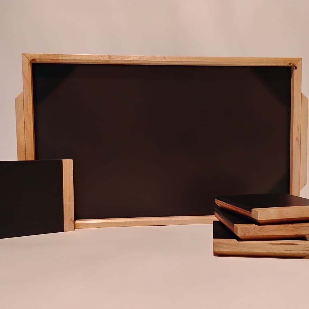 Small and large empty wooden chalkboards with a stack of wooden-framed boards.