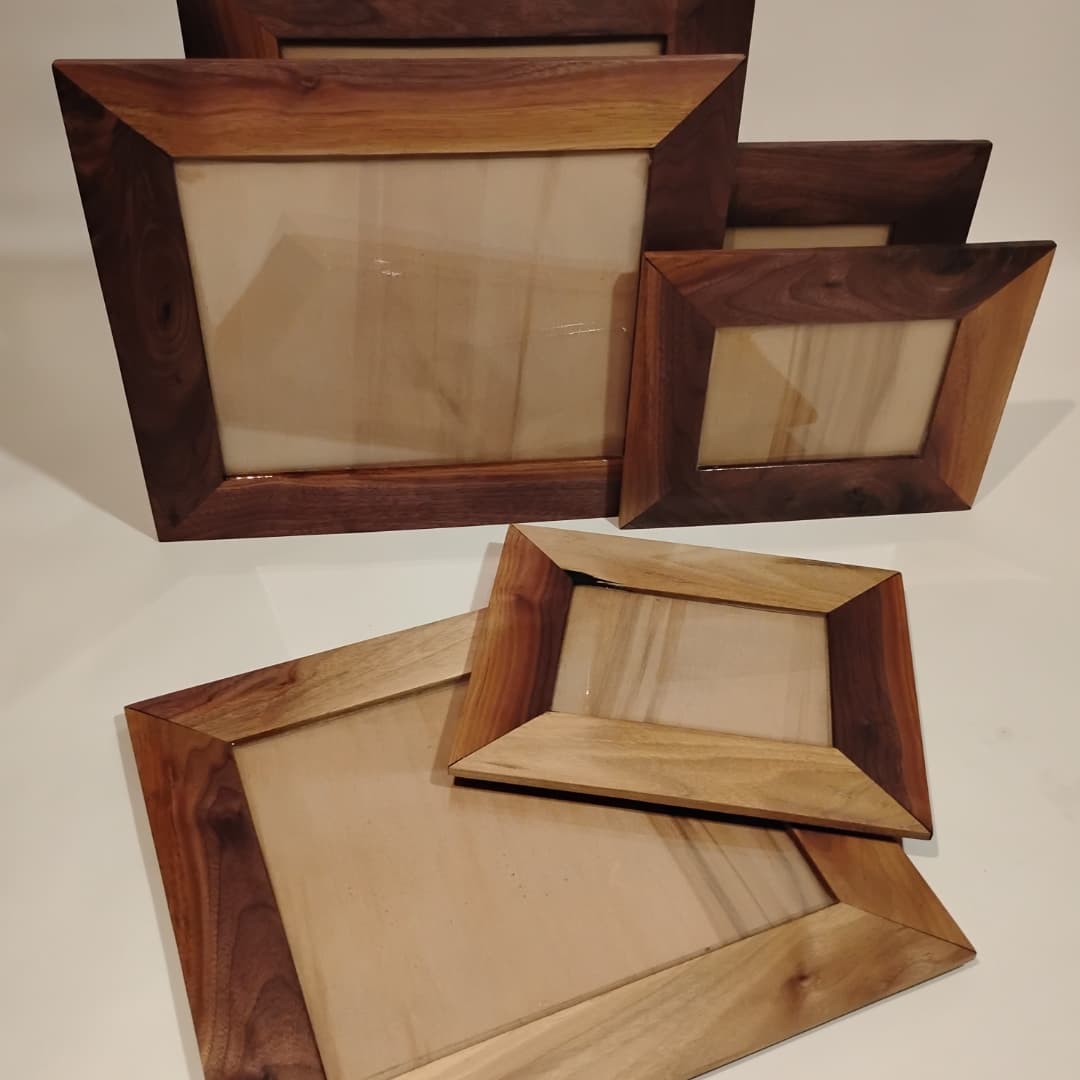 Four wooden picture frames of varying sizes on a plain surface.