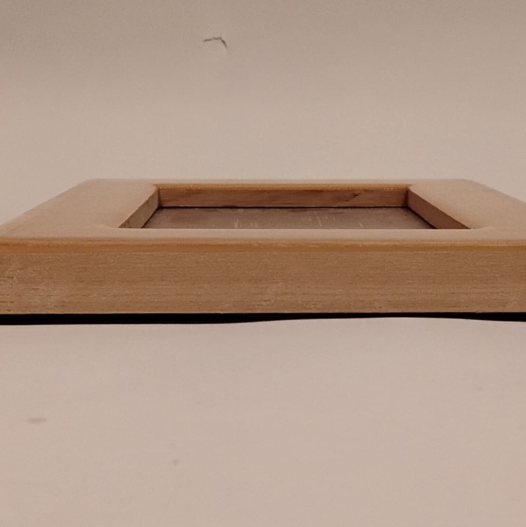 A wooden picture frame lying flat on a white surface.