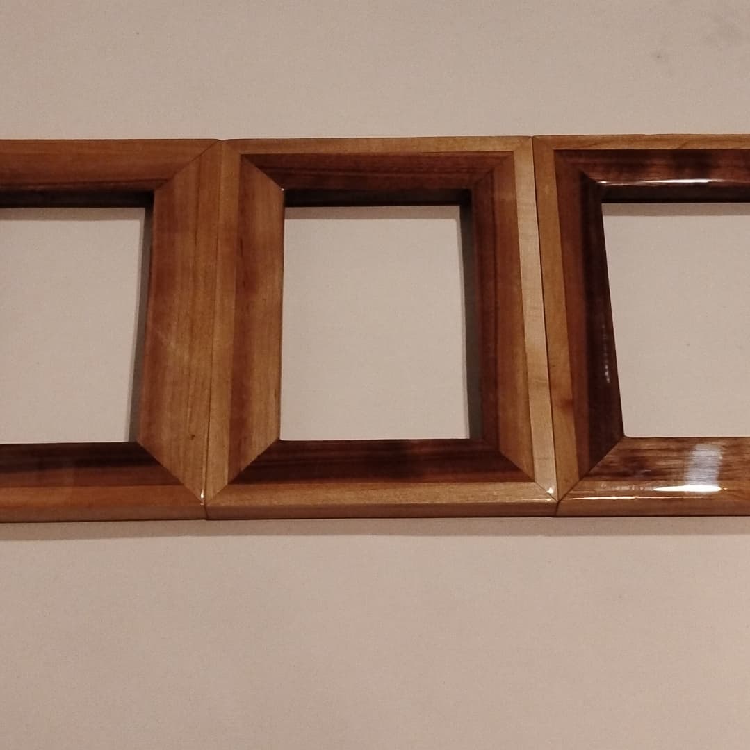 A wooden triple picture frame with an empty wall background.