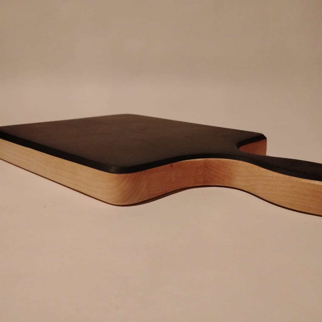 Side view of a wooden paddle with a dark rectangular top.