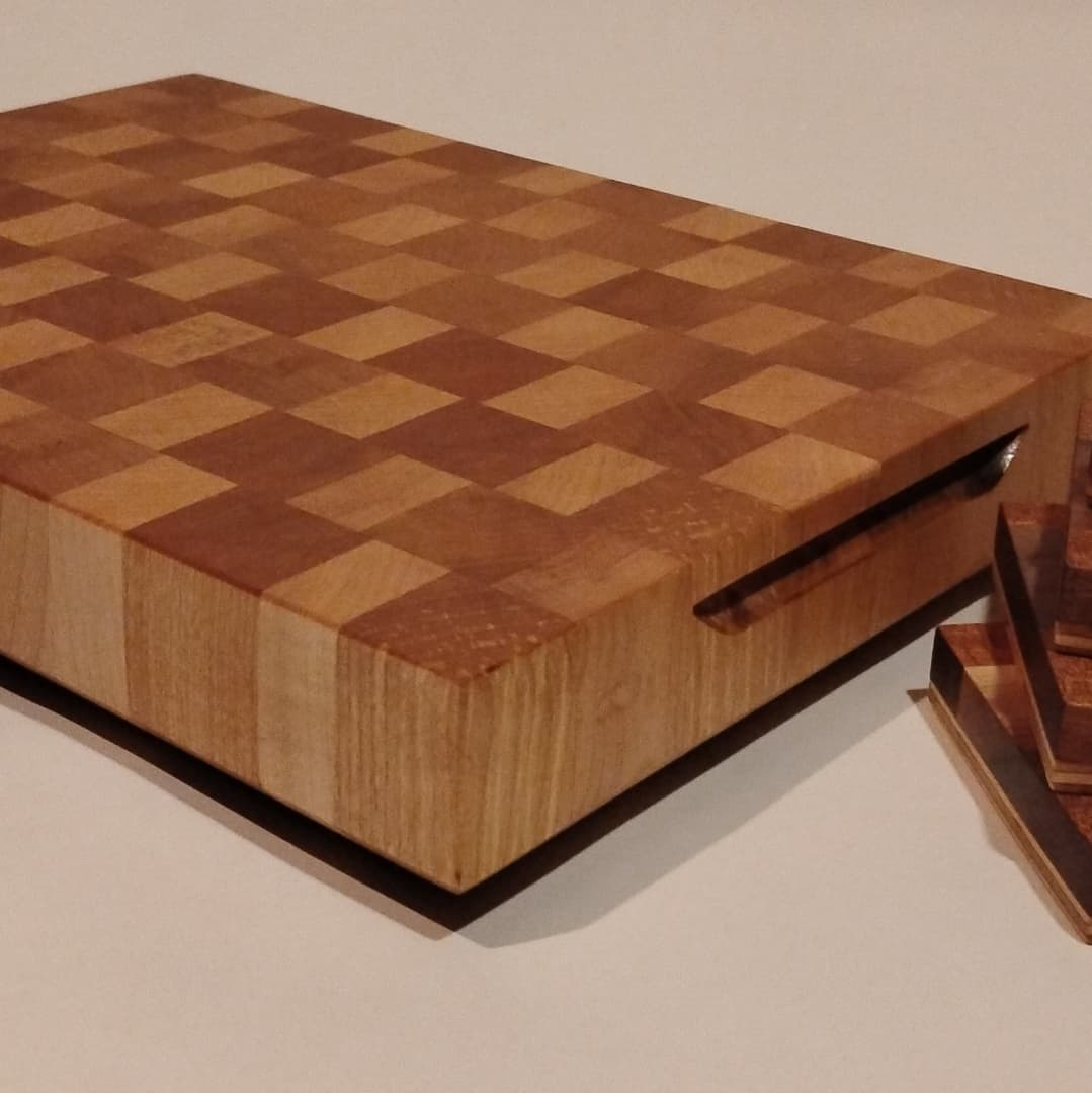 Wooden checkered cutting board with a juice groove and a knife.