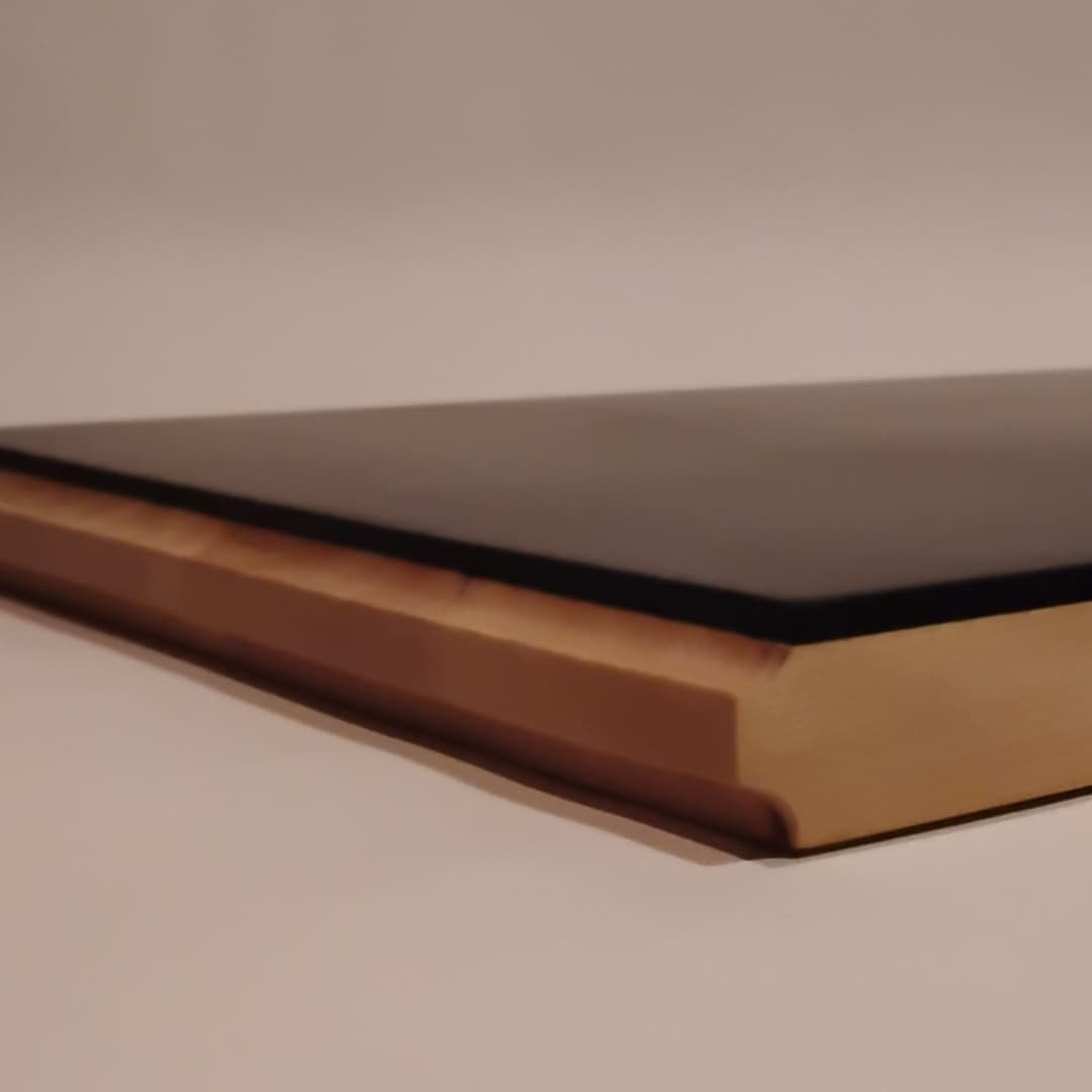A closed hardcover book with a black cover and gilded pages.