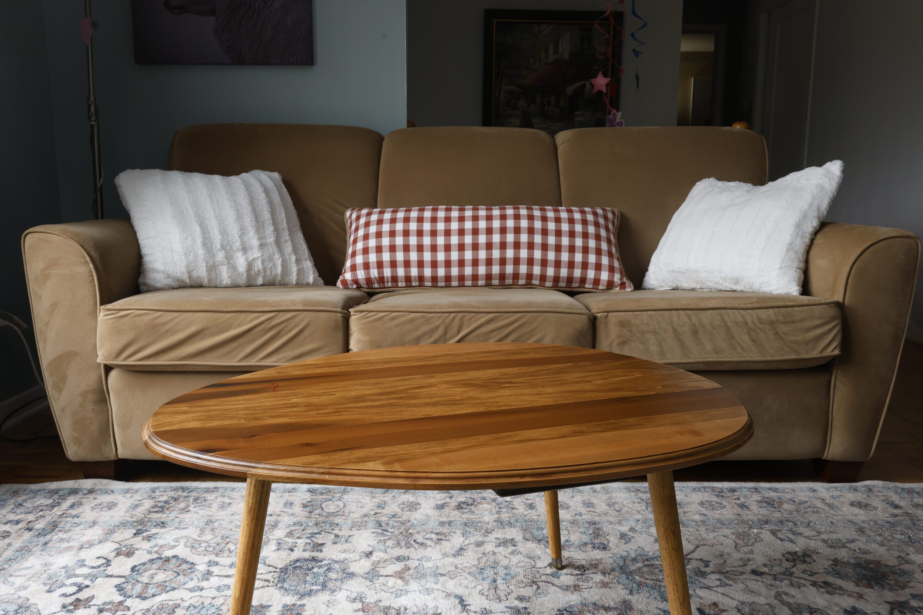 Wooden coffee table with a brown sofa and cushions in the background.