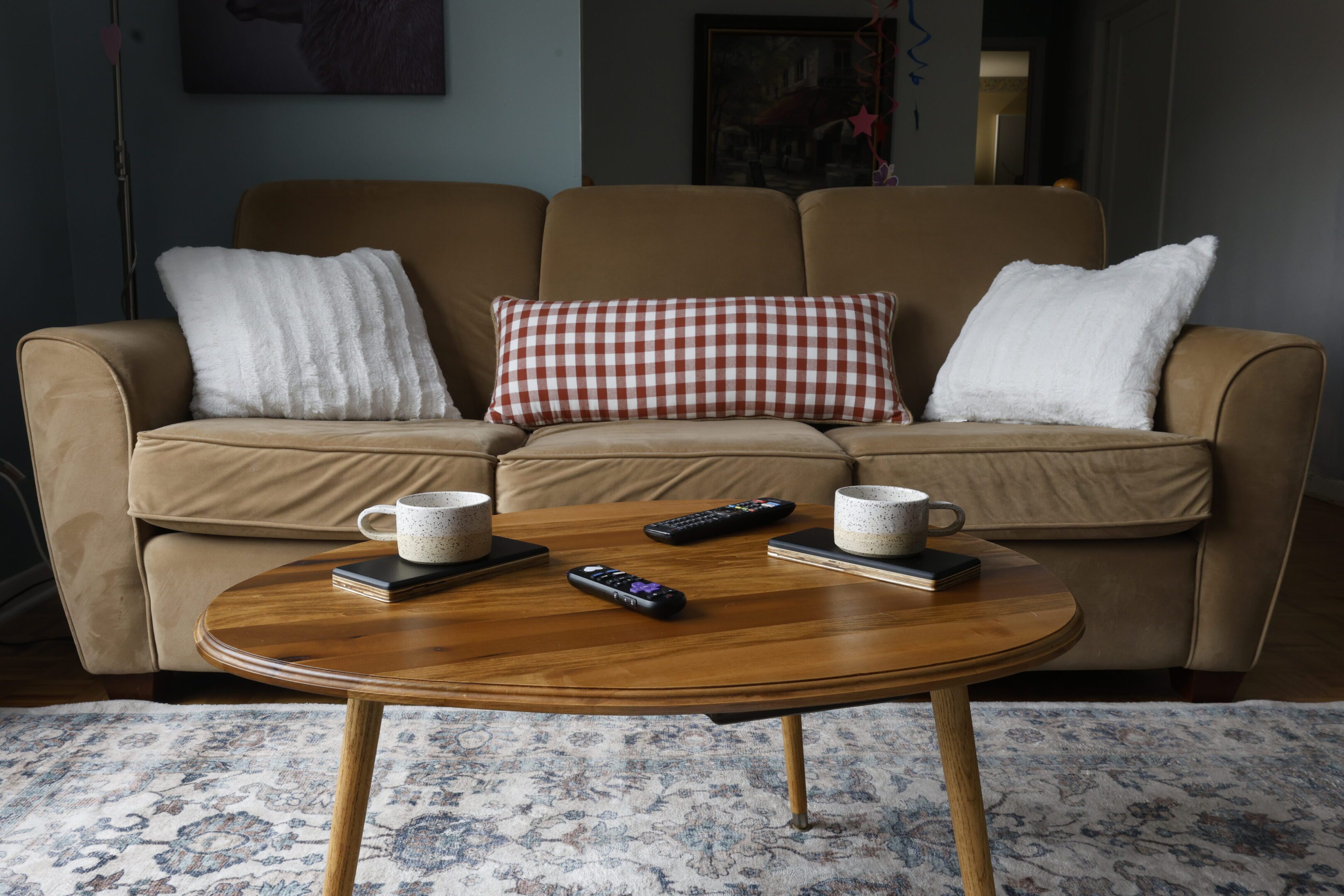 Cozy living room with coffee cups and remote on a wooden table.